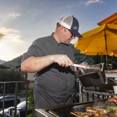 Koch beim Grillen auf der Terrasse